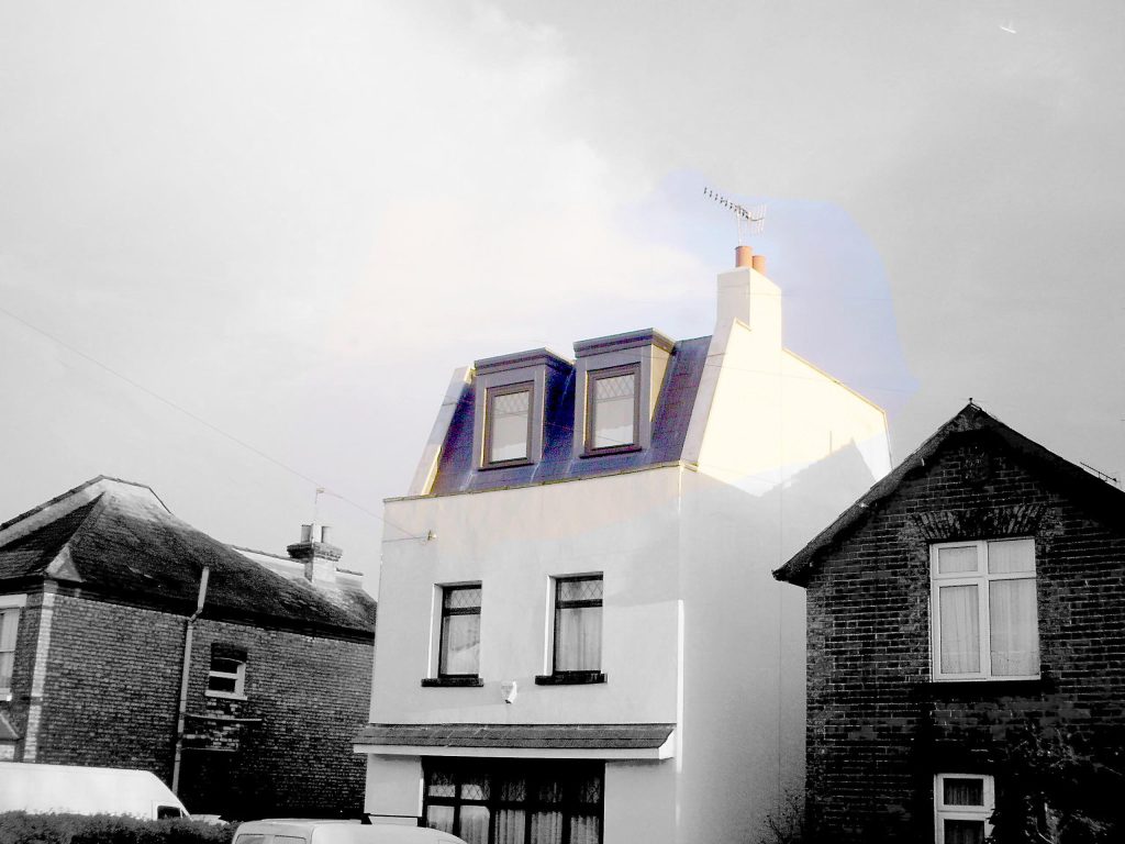 Modern loft conversion with large windows on a renovated house, enhancing space and value.