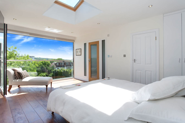 Loft conversion bedroom with wooden flooring and large window