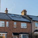 Modern loft conversion with skylights on a suburban brick home, showcasing added space and natural light.