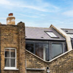 Modern loft conversion with roof windows in a brick building under a blue sky.