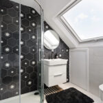 Modern loft bathroom with skylight, star-patterned tiles, and shower. Ideal conversion for maximizing space and light.