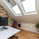 Modern loft conversion office with skylights, brick wall, and wooden floors. Perfect home workspace transformation.