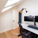 Modern loft conversion home office with skylight, dual monitors, and sleek design. Perfect workspace solution.