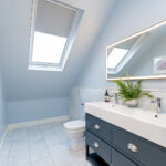 Modern loft conversion bathroom with skylight, elegant vanity, and marble flooring. Bright and spacious design.