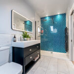 Modern loft conversion bathroom with blue tiled shower and sleek vanity. Ideal renovation inspiration.