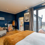 Modern loft conversion with cozy decor, blue walls, and city view. Optimal use of space and natural light.