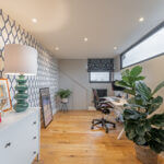 Stylish loft conversion home office with modern decor, vibrant plants, and geometric wallpaper design.