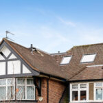 Charming loft conversion with skylights on a Tudor-style house, enhancing space and adding natural light.
