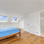Modern loft conversion with skylights, wooden floor, and en-suite bathroom. Bright and spacious home upgrade.