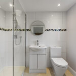 Modern loft conversion bathroom with glass shower, white tiles, and sleek fixtures. Perfect for small spaces.