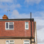Modern loft conversion with new windows and roof extension under a clear blue sky. Ideal home upgrade solution.