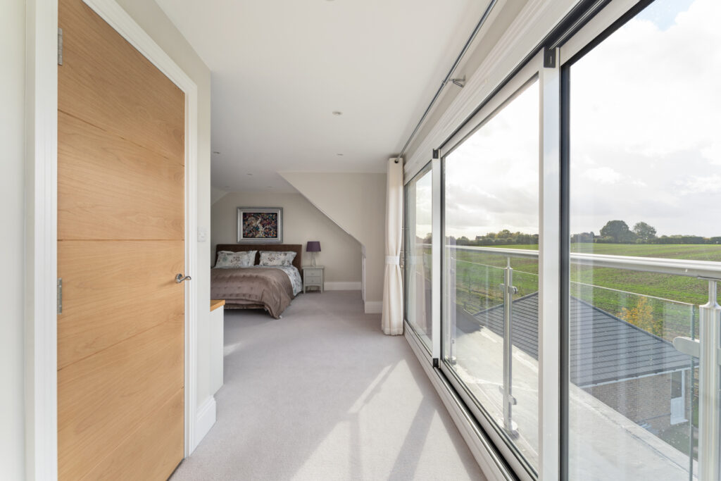 Modern loft conversion bedroom with large windows and scenic views, maximizing space and light. Ideal home renovation.