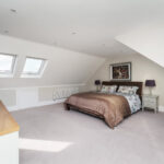 Bright modern loft conversion with skylights, cozy bed, and stylish decor. Perfect bedroom transformation for extra space.