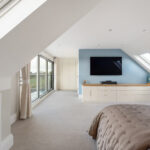 Spacious modern loft conversion with skylights, large windows, and a cozy bedroom setup for optimal natural light.