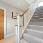 Modern loft conversion staircase with plush carpet and elegant wood railing, enhancing home space and design.