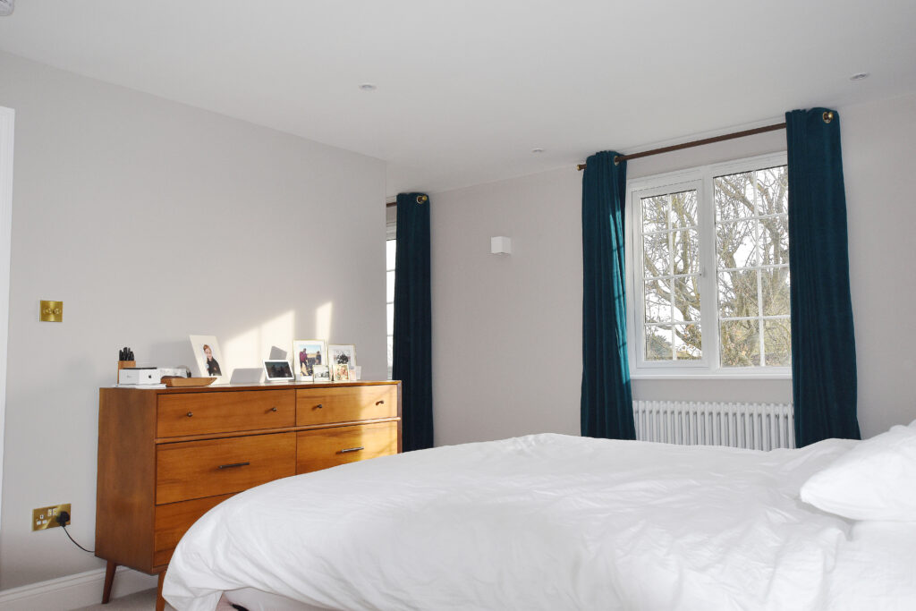 Bright, modern loft conversion bedroom with elegant furniture and large window, showcasing natural light and style.